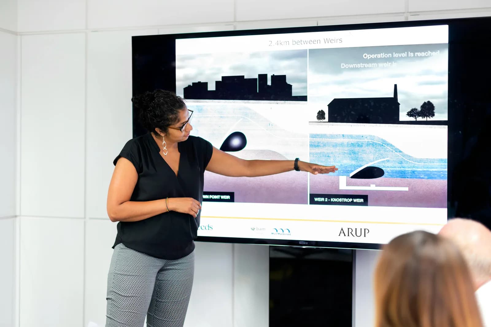A presenter pointing at content on a large wall-mounted display