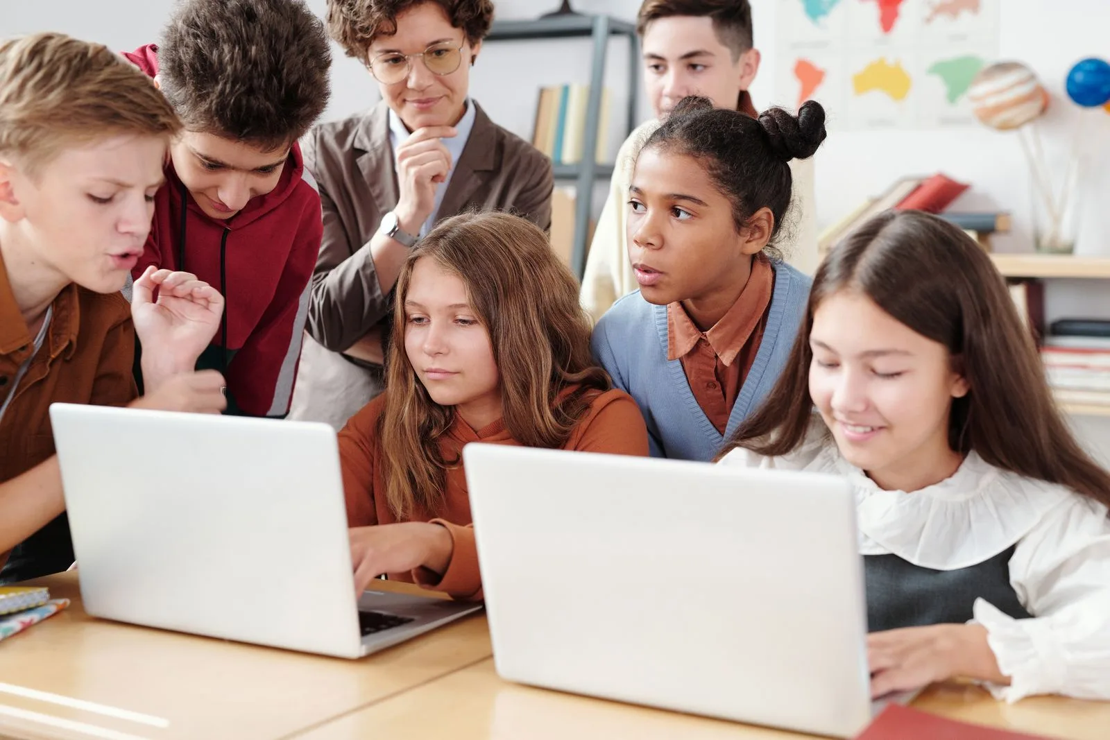Students and a teacher collaborating on laptops